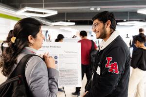 A man and a woman having a conversation in front of a research poster