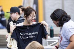 A student holding up a Northeastern University t-shirt