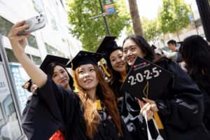 Photo by Ruby Wallau. A group of graduates pose for a photo outside the theater