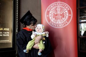 Photo by Ruby Wallau. A graduate kisses the head of an infant