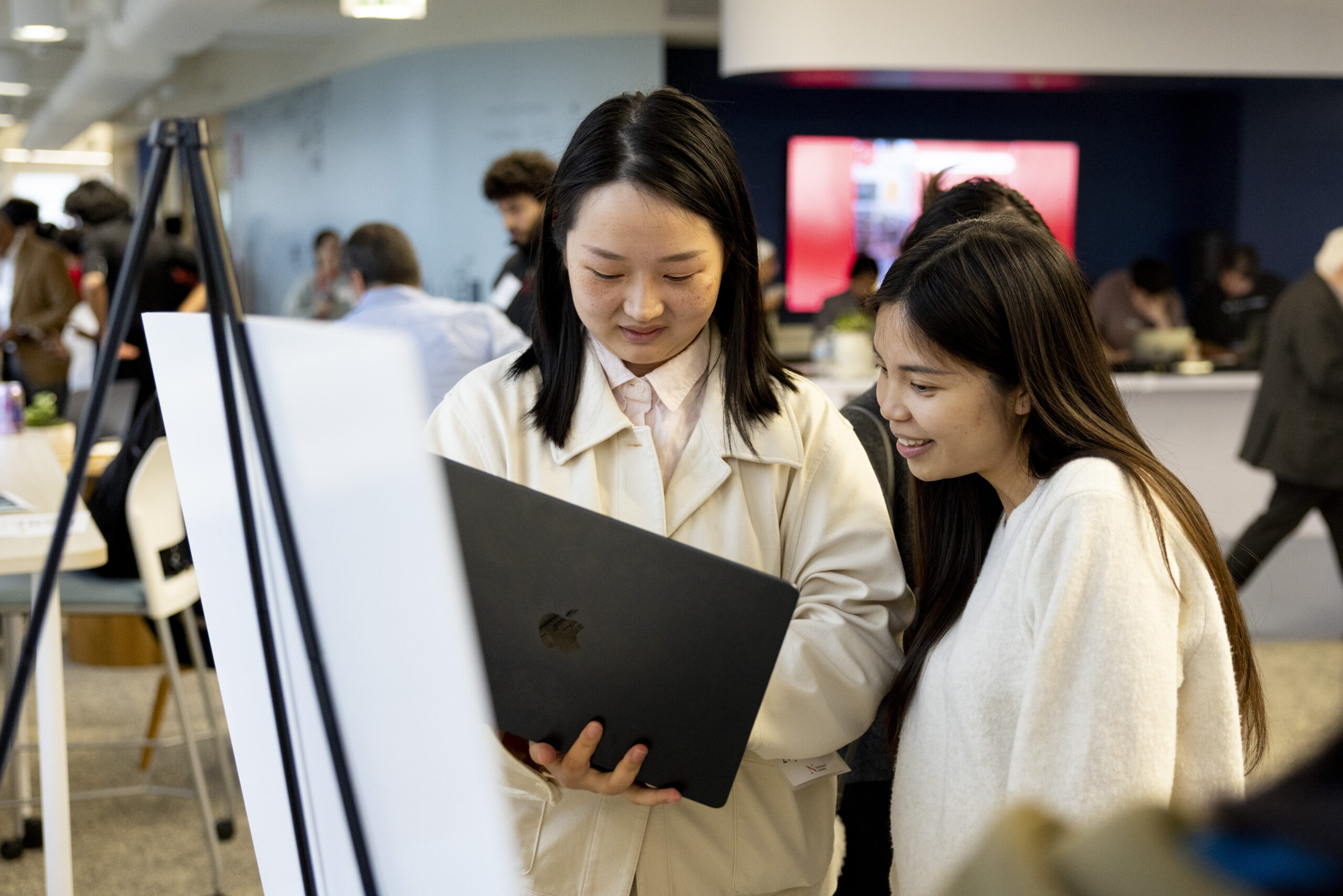 Two women look at a laptop during the student research showcase 2025