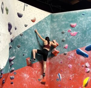 A photo of a student nearing the top of an indoor climbing wall