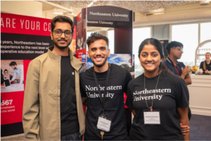 Mandar smiles in the middle of the photo wearing a Northeastern t-shirt, with arms around two other students on either side of him, all smiling