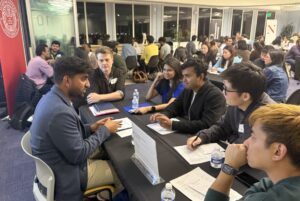 A group of students listen to a professional volunteer speaking about his experience and sharing advice