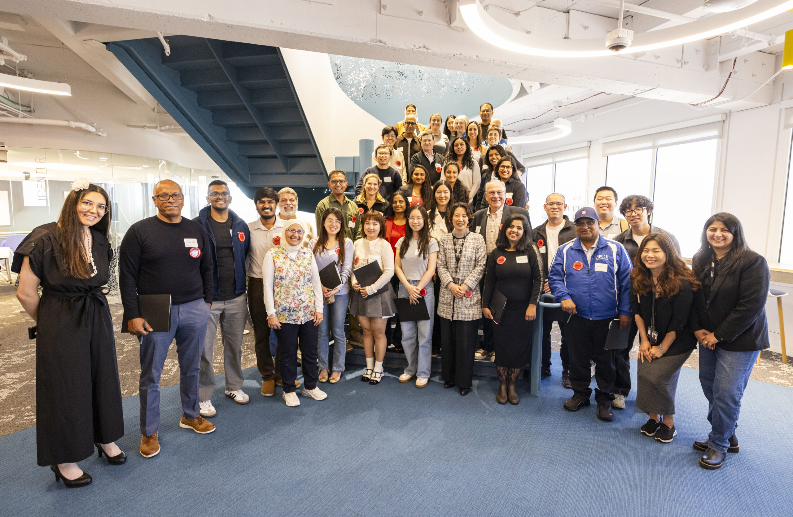 A group photo of many of the judges gathered on campus. The group is positioned on the stairs between the two campus floors, with about 40 people pictured.